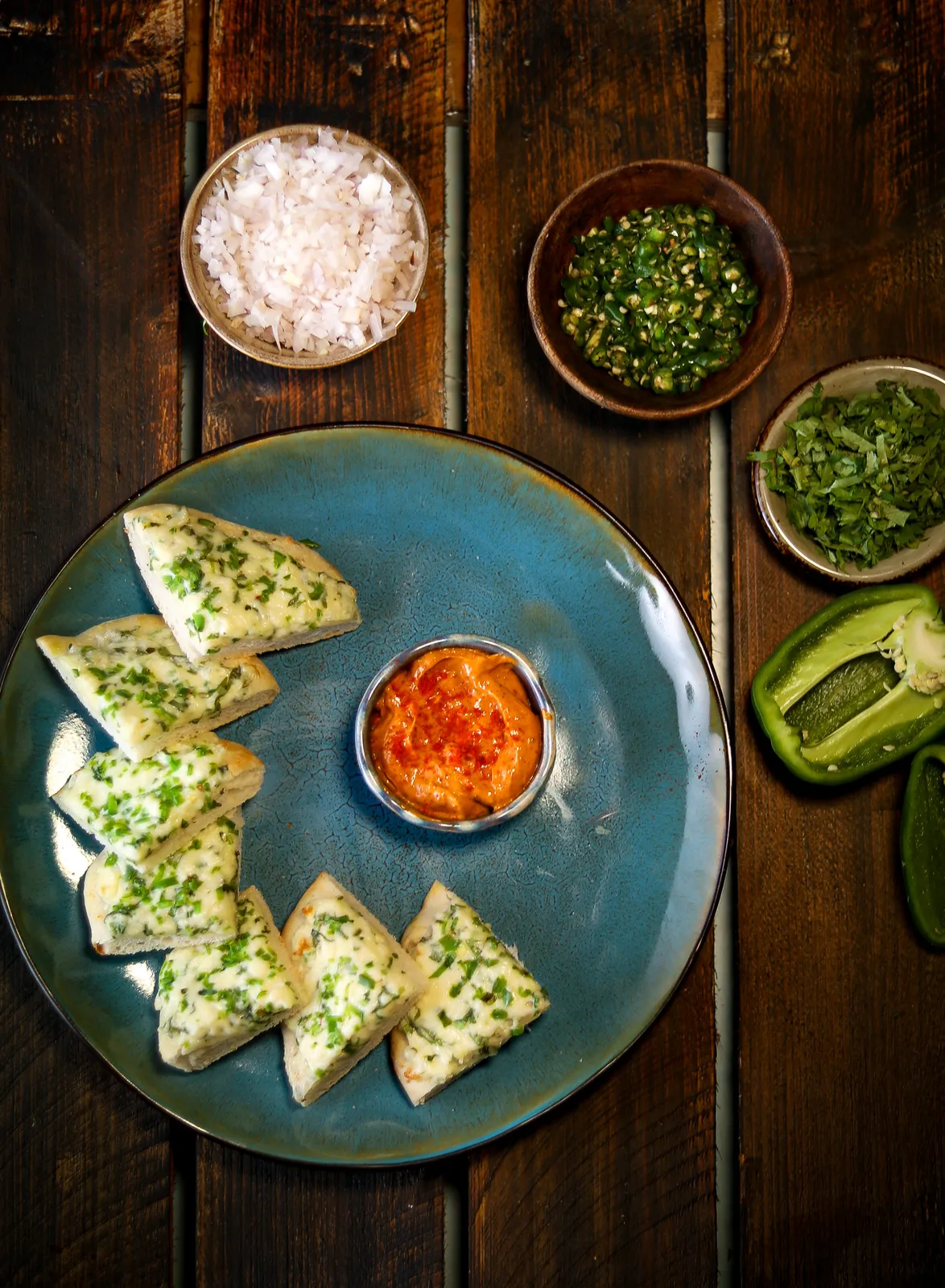 A plated cheesy kulcha served with dip.